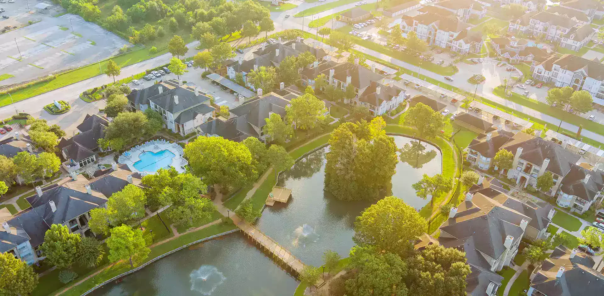 Aerial drone shot of a residential neighborhood and community pond in Texas.