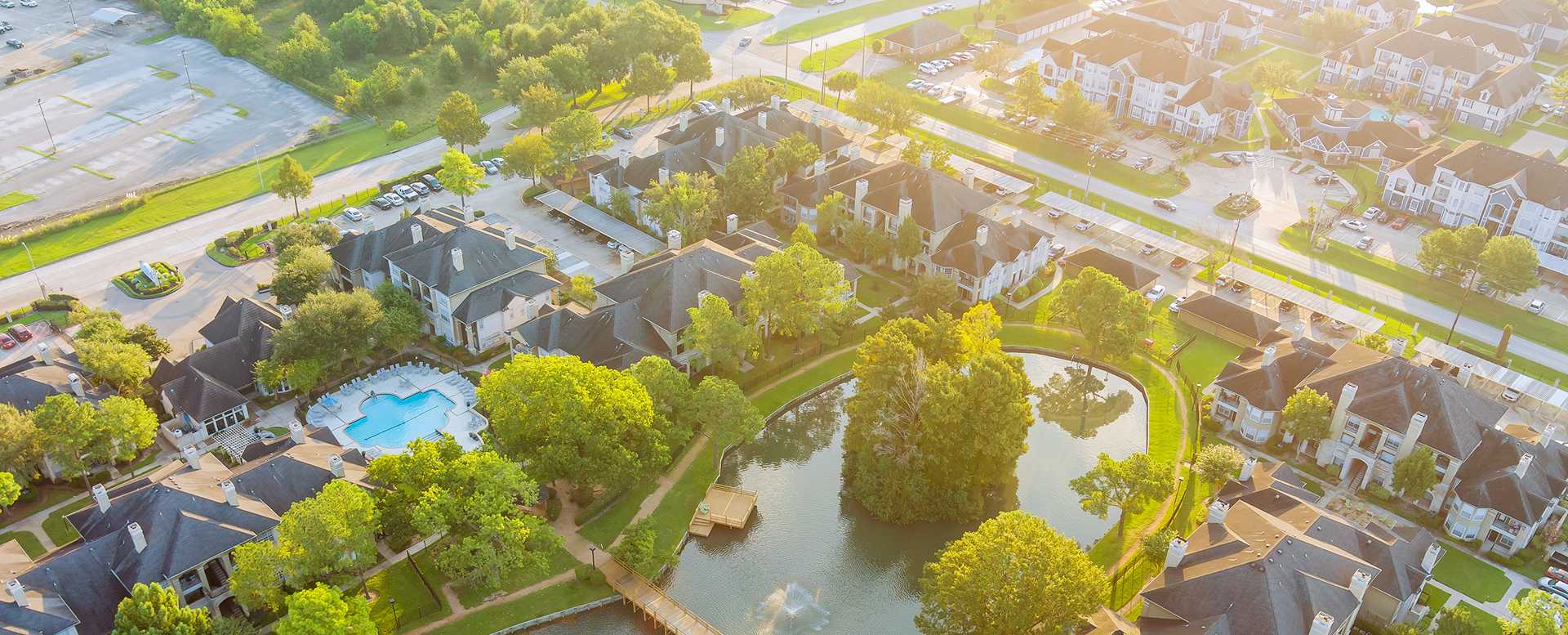 Aerial drone shot of a residential neighborhood and community pond in Texas.